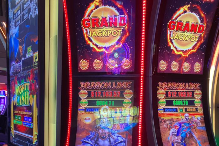 A bank of Dragon Link slot machines in a casino with bright lights and buttons flashing