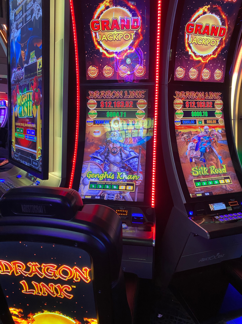 Bank of Dragon Link slot machines inside a casino with chairs and bright lights